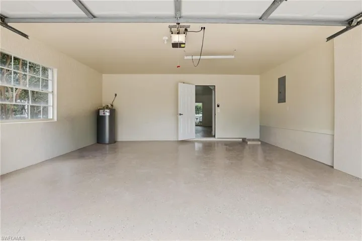 Garage with a textured wall, water heater, and electric panel