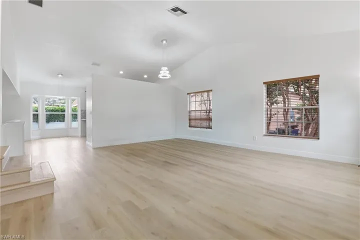 Unfurnished living room featuring light wood-style floors and vaulted ceiling