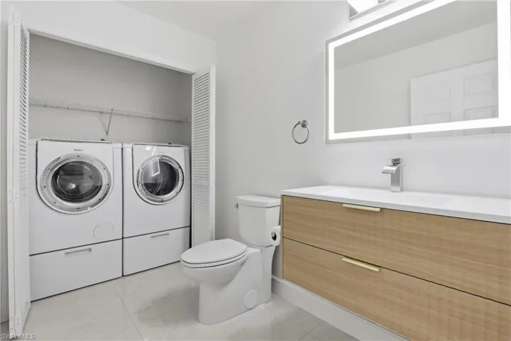 Bathroom with vanity, washer and dryer, and a closet