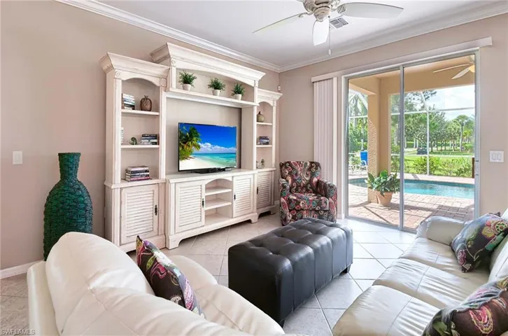 Living area with a ceiling fan, light tile patterned floors, ornamental molding, and baseboards