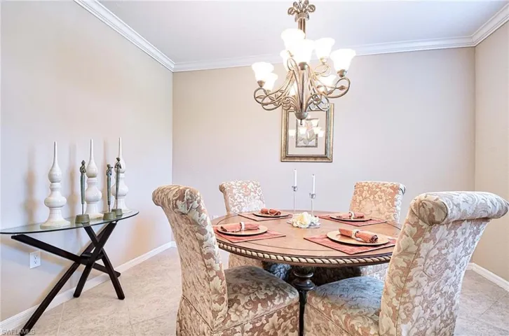 Dining space featuring ornamental molding, a chandelier, baseboards, and tile patterned flooring