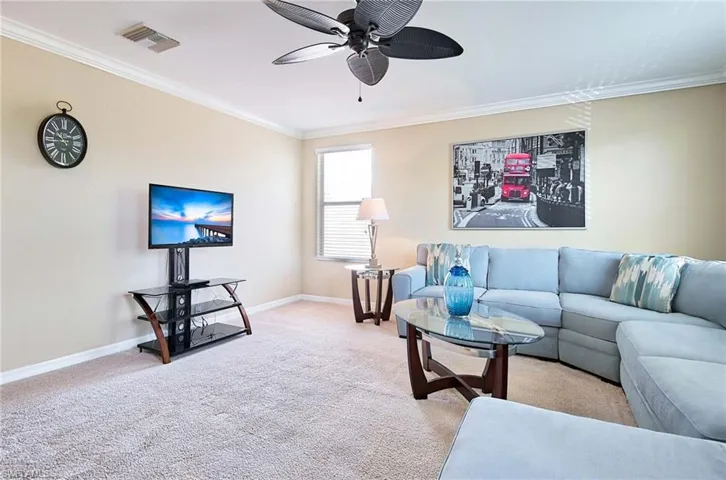 Living area with crown molding, a ceiling fan, carpet, and baseboards
