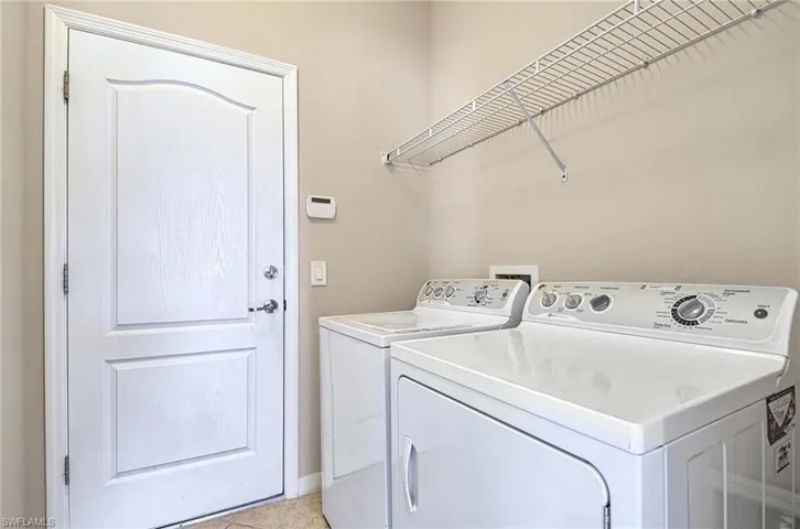 Washroom featuring separate washer and dryer, baseboards, and light tile patterned flooring