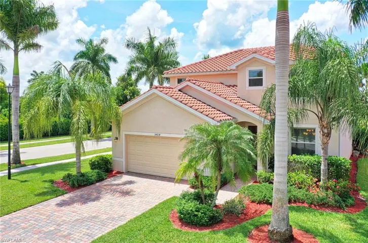 Mediterranean / spanish home with a tile roof, stucco siding, decorative driveway, an attached garage, and a front lawn