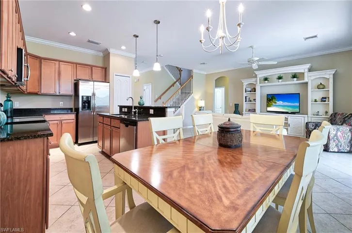 Dining room with light tile patterned floors, stairway, ornamental molding, ceiling fan, and arched walkways