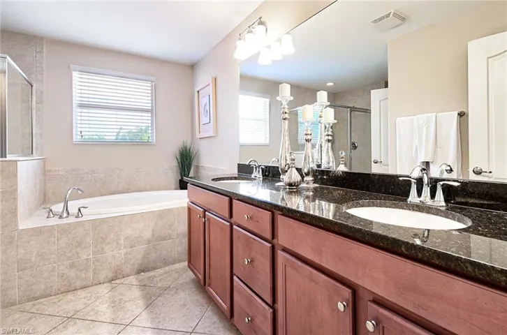 Bathroom featuring tile patterned floors, a stall shower, double vanity, and a bath
