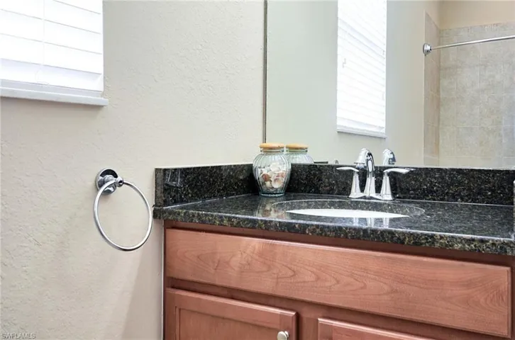 Full bathroom with vanity, a textured wall, and a shower
