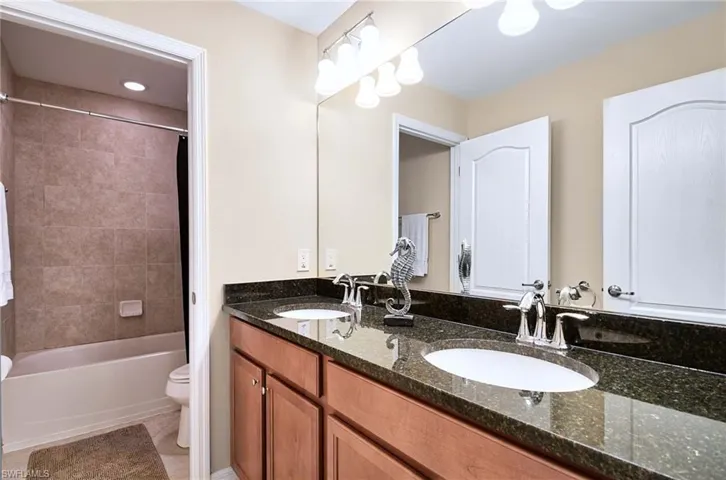 Full bath with toilet, double vanity, shower / bathtub combination, and tile patterned flooring