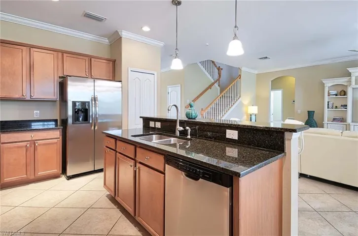 Kitchen featuring stainless steel appliances, a sink, light tile patterned flooring, ornamental molding, and open floor plan