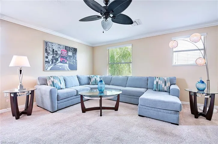 Living area featuring carpet flooring, ornamental molding, plenty of natural light, ceiling fan, and baseboards