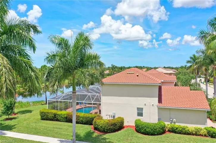 View of side of home with a lawn, a tiled roof, stucco siding, and glass enclosure