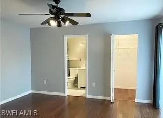 Unfurnished bedroom featuring dark wood-style flooring, a ceiling fan, and a spacious closet
