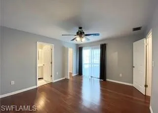 En-suite bedroom with dark wood-style floors and a ceiling fan