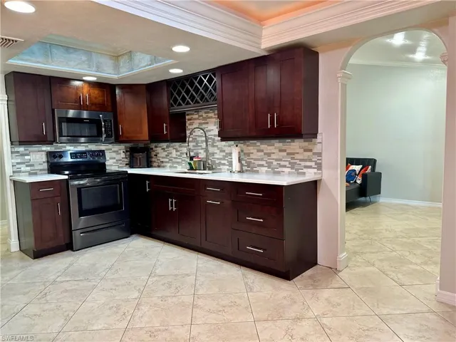 Kitchen with crown molding, decorative backsplash, sink, and stainless steel appliances