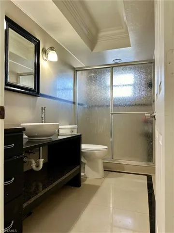 Bathroom featuring walk in shower, crown molding, vanity, and toilet