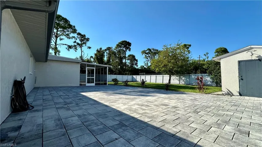 View of patio with a storage unit and a sunroom