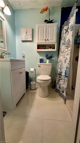 Bathroom featuring tile patterned floors, curtained shower, vanity, and toilet