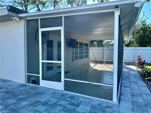 View of property exterior featuring french doors, a sunroom, and a patio area