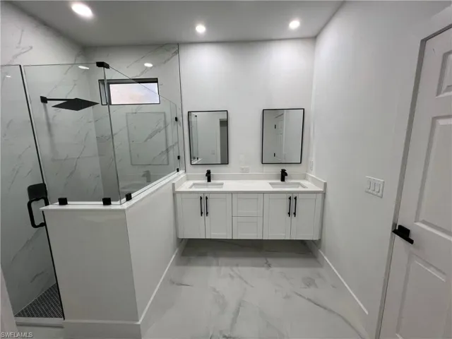 Bathroom featuring walk in shower, tile flooring, vanity with extensive cabinet space, and double sink