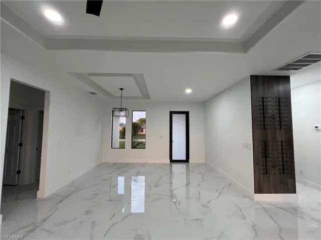 Unfurnished room featuring a raised ceiling and light tile floors