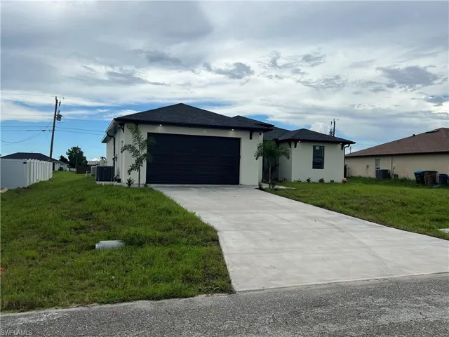 View of front of house with central AC, a front lawn, and a garage