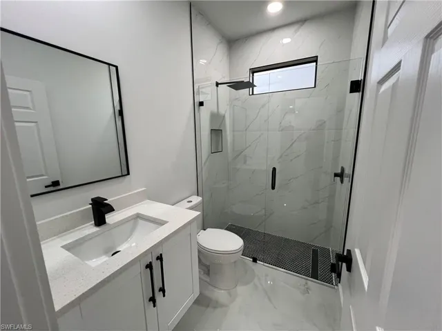 Bathroom featuring walk in shower, tile flooring, vanity, and toilet