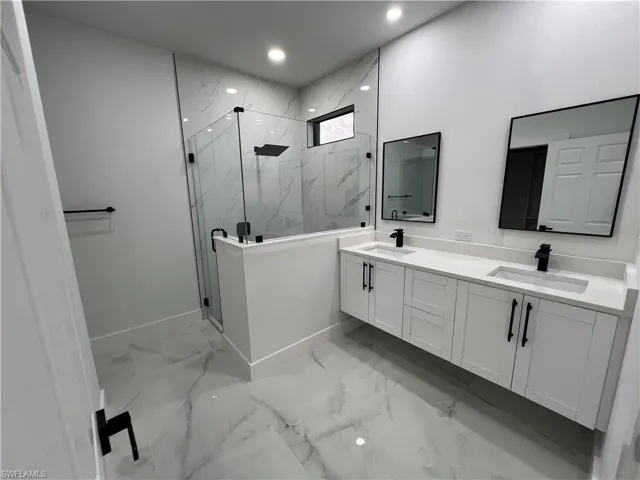Bathroom featuring tile floors, dual bowl vanity, and an enclosed shower