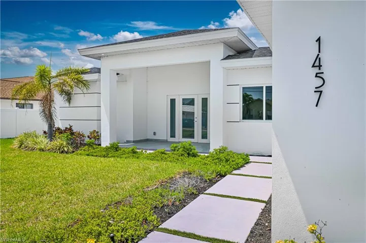 Property entrance featuring french doors, a yard, and stucco siding