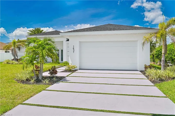 View of front of property featuring stucco siding, an attached garage, a front yard, and driveway