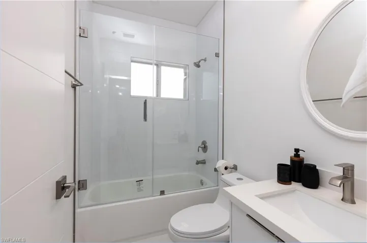 Bathroom featuring vanity and shower / bath combination with glass door