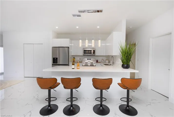 Kitchen featuring appliances with stainless steel finishes, modern cabinets, a breakfast bar area, light marble finish flooring, and recessed lighting