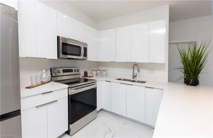 Kitchen with appliances with stainless steel finishes, light marble finish floors, and light countertops