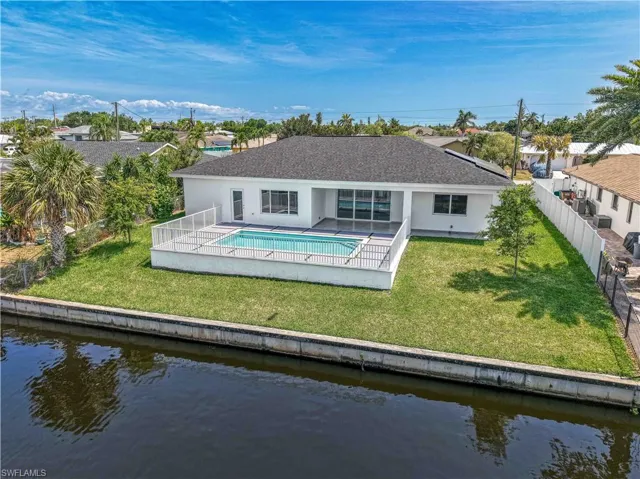 Back of property with a water view, stucco siding, and a fenced backyard