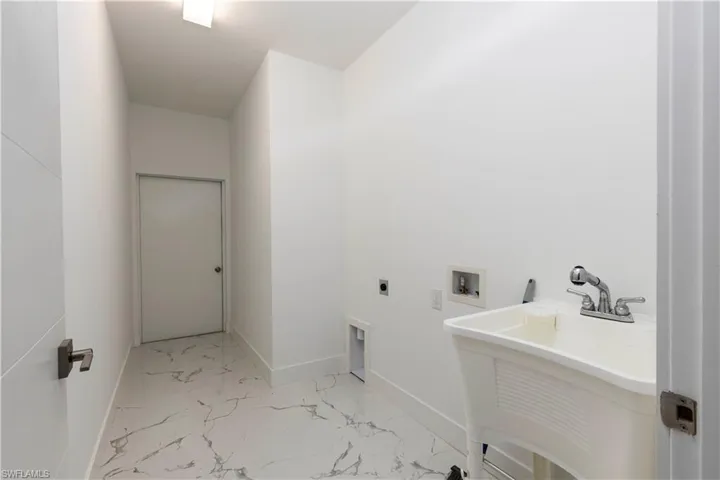 Laundry room with electric dryer hookup, marble look tile flooring, and washer hookup