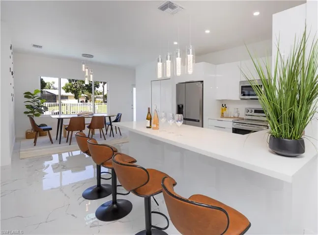 Kitchen with appliances with stainless steel finishes, modern cabinets, light countertops, light marble finish flooring, and recessed lighting