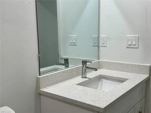 Half bathroom featuring vanity and a textured wall