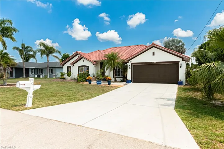 Mediterranean / spanish-style home with a garage and a front lawn