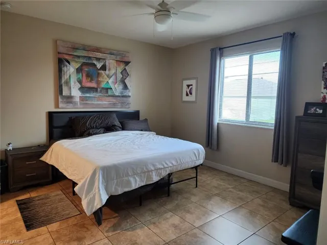 Tiled bedroom featuring ceiling fan