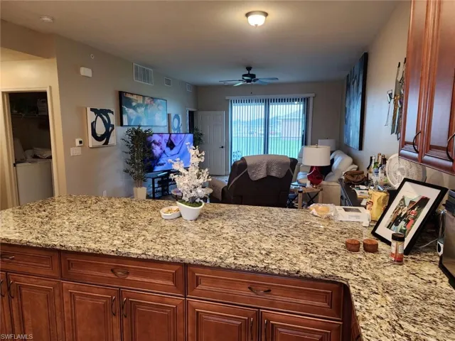 Kitchen with light stone countertops, ceiling fan, and washer and clothes dryer