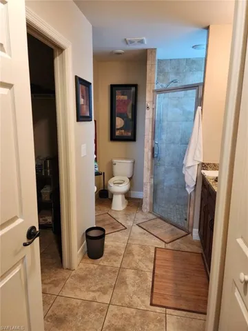 Bathroom with tile patterned flooring, vanity, toilet, and an enclosed shower