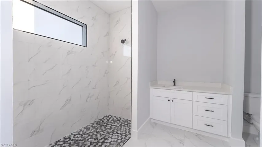 Bathroom with a tile shower, vanity, and toilet