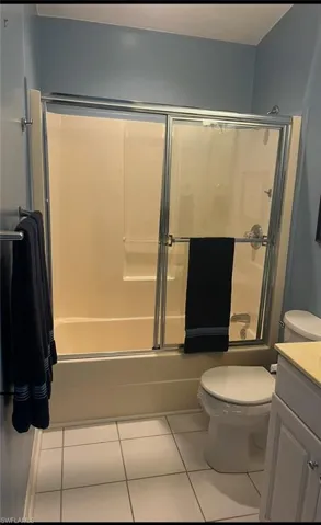 Full bathroom featuring vanity, combined bath / shower with glass door, tile patterned floors, and toilet