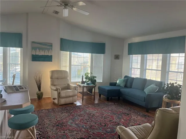 Living room featuring dark hardwood / wood-style floors, vaulted ceiling, and a wealth of natural light