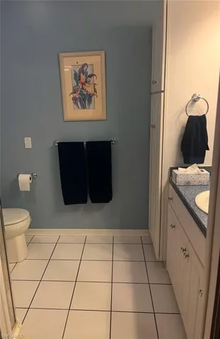 Master Bathroom with linen closet, tile flooring, shower, vanity, and toilet
