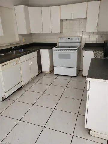 Kitchen featuring white cabinets, white appliances, and sink