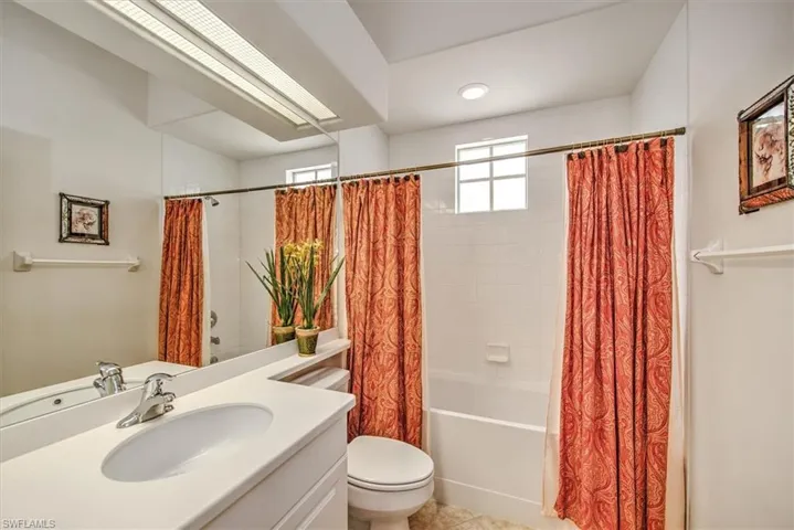Full bathroom with vanity, shower / bathtub combination with curtain, tile patterned flooring, and toilet