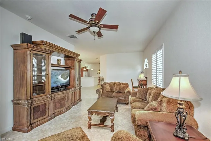 Living room featuring light tile patterned floors and ceiling fan