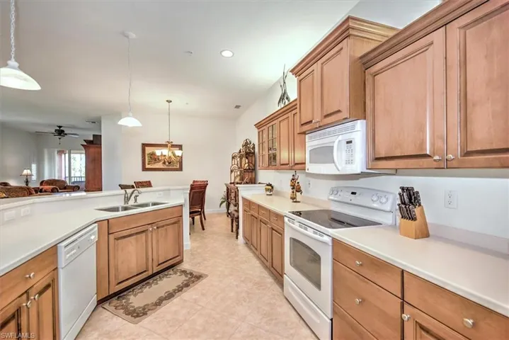 Kitchen with ceiling fan with notable chandelier, pendant lighting, white appliances, sink, and light tile patterned floors