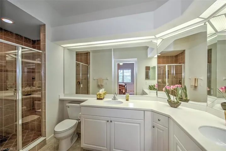 Bathroom with vanity, a shower with door, tile patterned floors, and toilet