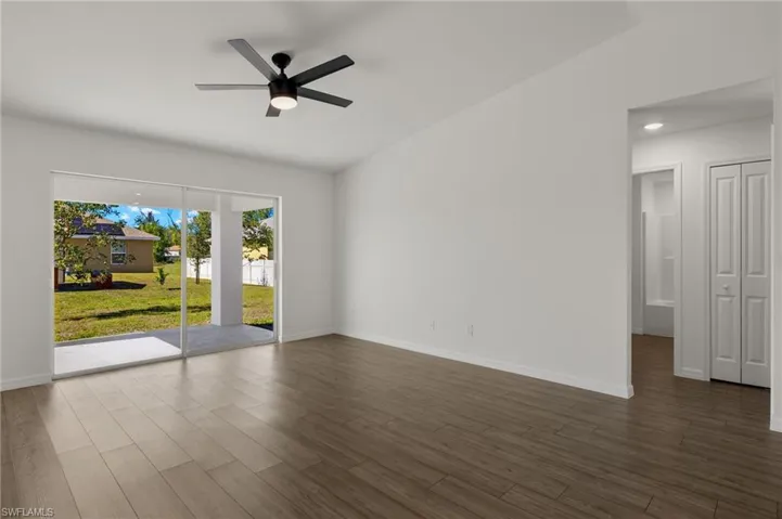 Spare room with a ceiling fan, dark wood-style flooring, and baseboards